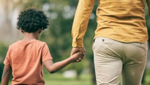 Generations holding hands in nature symbolizing legacy and future impact